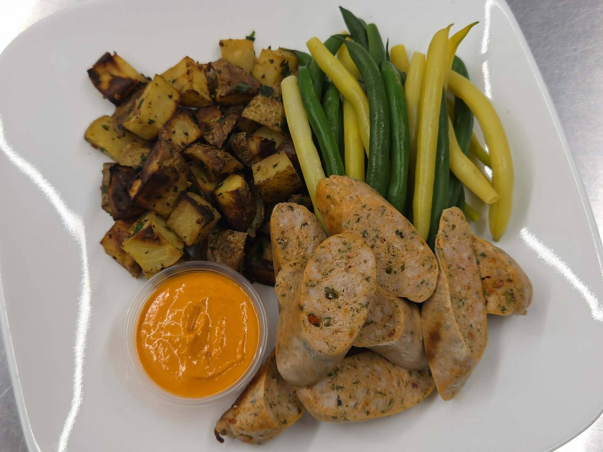 Saucisses de poulet créoles, pommes de terres rôties au four, haricots jaunes et verts
